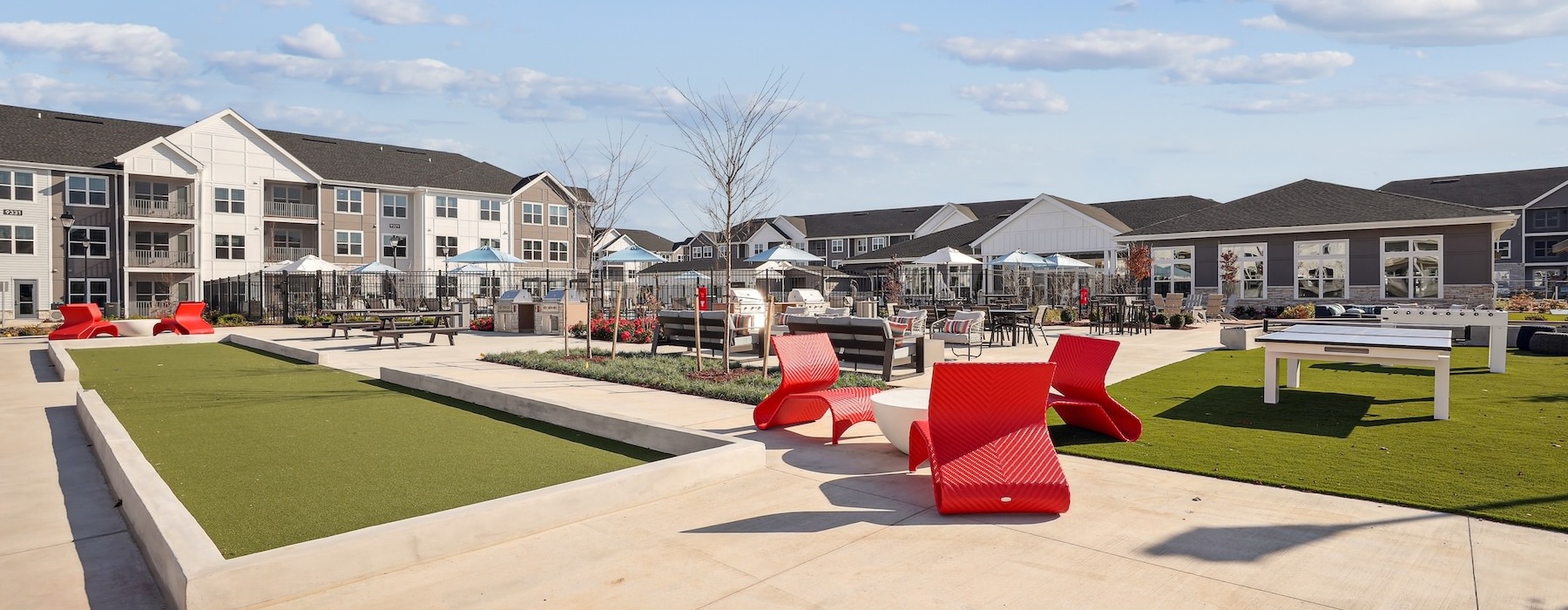a courtyard with red chairs and a building in the background