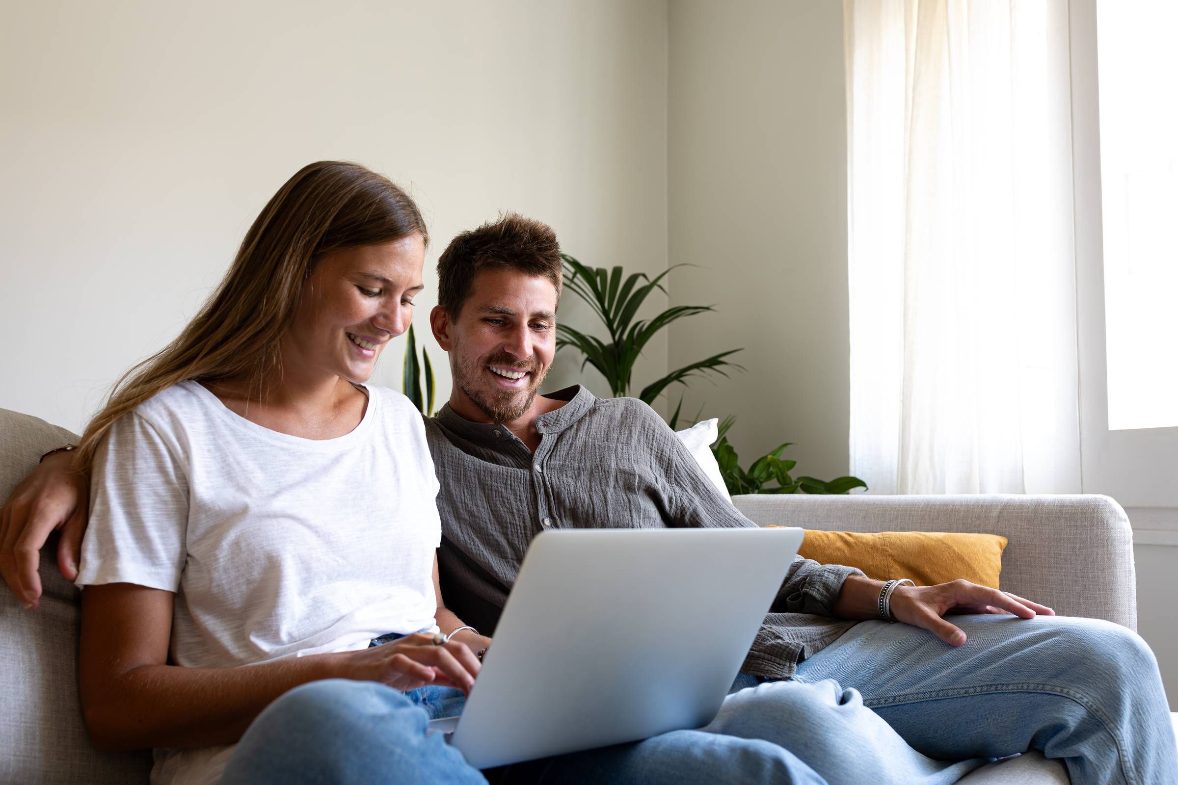 Alta Cosner Luxury Apartments with a couple sitting on the couch together and smiling while looking at a laptop